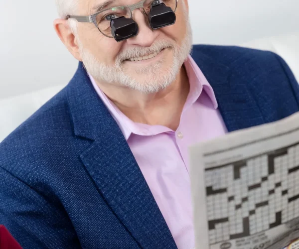 Man wearing bioptic telescope glasses while reading the newspaper